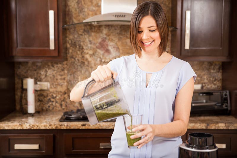 Happy young woman about to drink some healthy green juice as part of a detox diet. Happy young woman about to drink some healthy green juice as part of a detox diet