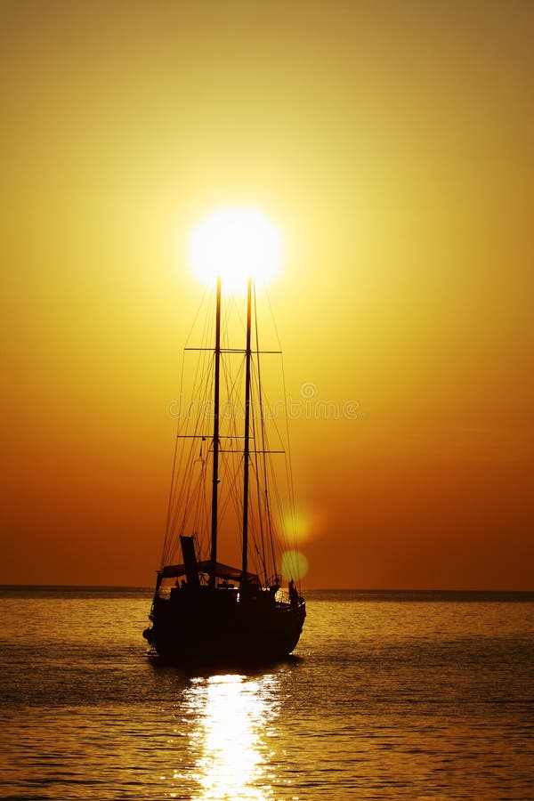 A silhouette of a sailboat in the sunset