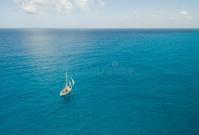 Sailboat in Bright Blue Water - Aerial View - Isla Mujeres, Mexico. Sailboat with sails up in brilliant blue water off the coast of Isla Mujeres, Mexico near stock photography Sailboat in Bright Blue Water - Aerial View - Isla Mujeres, Mexico. Sailboat with sails up in brilliant blue water off the coast of Isla Mujeres, Mexico near stock photography