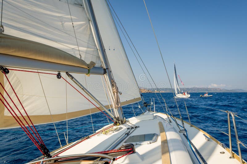 Sailing boat going fast on she s sails, view from the cockpit to bow.