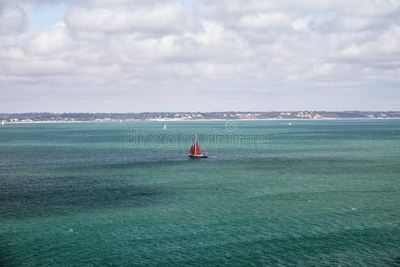 Sailing Yacht With Red Sail Goes On The Turquoise Sea Stock Photo