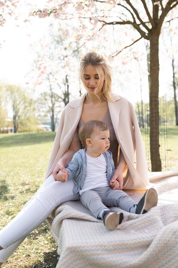SAKURA Cherry Blossom - Young mom mother sitting with her little boy baby son in a park in Riga, Latvia Europe stock images SAKURA Cherry Blossom - Young mom mother sitting with her little boy baby son in a park in Riga, Latvia Europe stock images