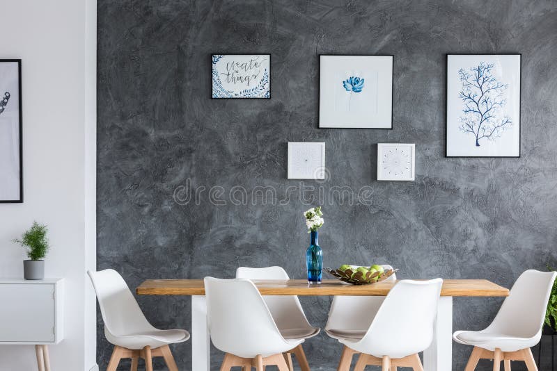 Flowers in blue glass vase on wooden table in monochromatic dining room with gallery on wall. Flowers in blue glass vase on wooden table in monochromatic dining room with gallery on wall