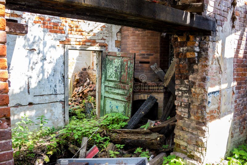 Sala desarrumada de uma casa abandonada velha, de uma porta quebrada e de uma chaminé velha do tijolo imagem de stock Sala desarrumada de uma casa abandonada velha, de uma porta quebrada e de uma chaminé velha do tijolo imagem de stock