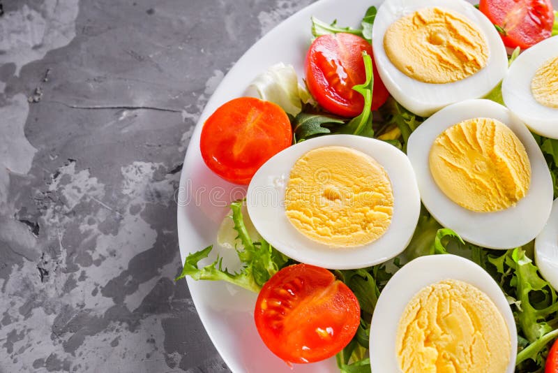 Salad with boiled chicken eggs and cherry tomatoes on a stone background