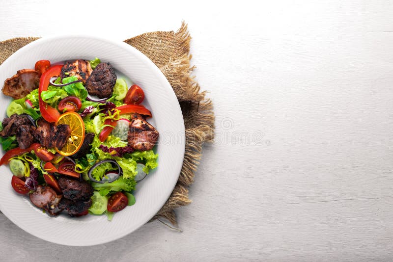 Salad with fresh cucumbers, tomatoes and greens with grilled meat on a plate Wooden board.