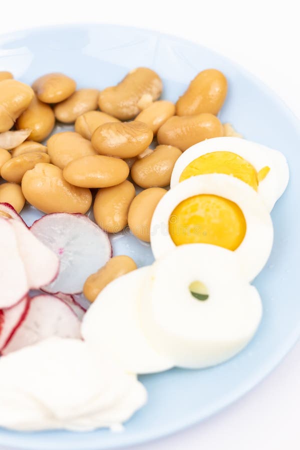 Salad med skivade kokta ägg, kokta bönor, skivade radisor och surgrädde royaltyfri bild Salad med skivade kokta ägg, kokta bönor, skivade radisor och surgrädde royaltyfri bild