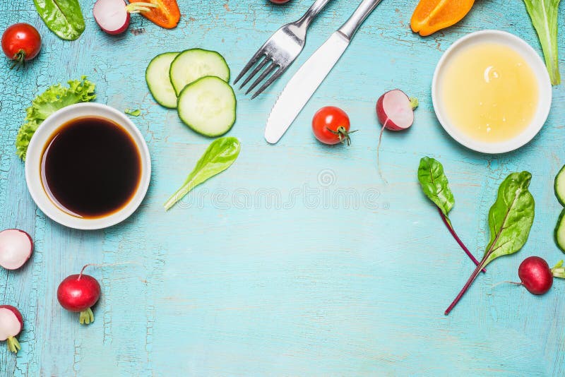 Salad preparation with cutlery dressing ingredients , lettuce , herbs and vegetables on light blue wooden background, top view