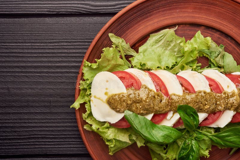 A salada caprese deliciosa com tomates e mozzarella maduros com manjericão fresca sae Alimento italiano imagem de stock royalty free A salada caprese deliciosa com tomates e mozzarella maduros com manjericão fresca sae Alimento italiano imagem de stock royalty free