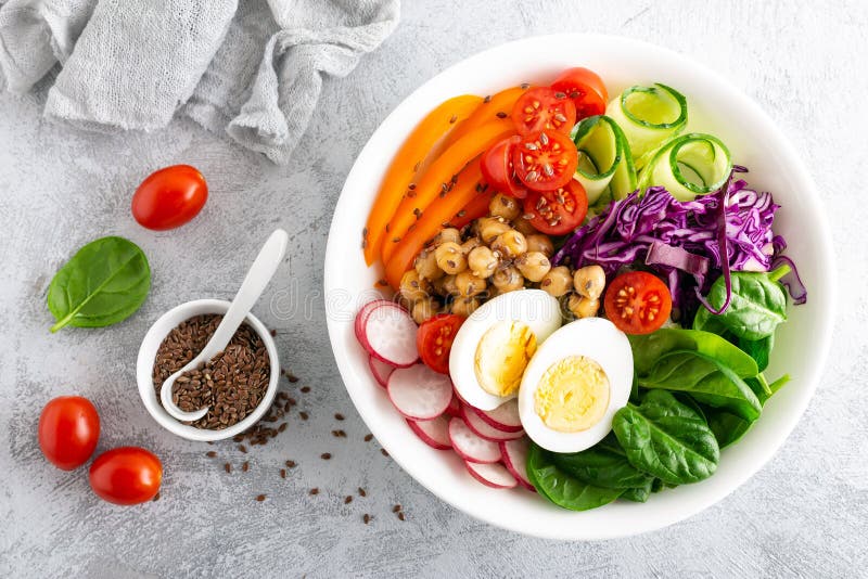 Buddha bowl salad with chickpeas, sweet pepper, tomato, cucumber, red cabbage kale, fresh radish, spinach leaves and boiled egg, healthy eating concept, top view, flat lay. Buddha bowl salad with chickpeas, sweet pepper, tomato, cucumber, red cabbage kale, fresh radish, spinach leaves and boiled egg, healthy eating concept, top view, flat lay