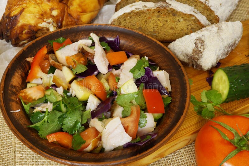 A salada de frango saudável com tomates, a couve, as maçãs e a pimenta vermelha em uma argila rolam Vegetais crus fotografia de stock royalty free A salada de frango saudável com tomates, a couve, as maçãs e a pimenta vermelha em uma argila rolam Vegetais crus fotografia de stock royalty free