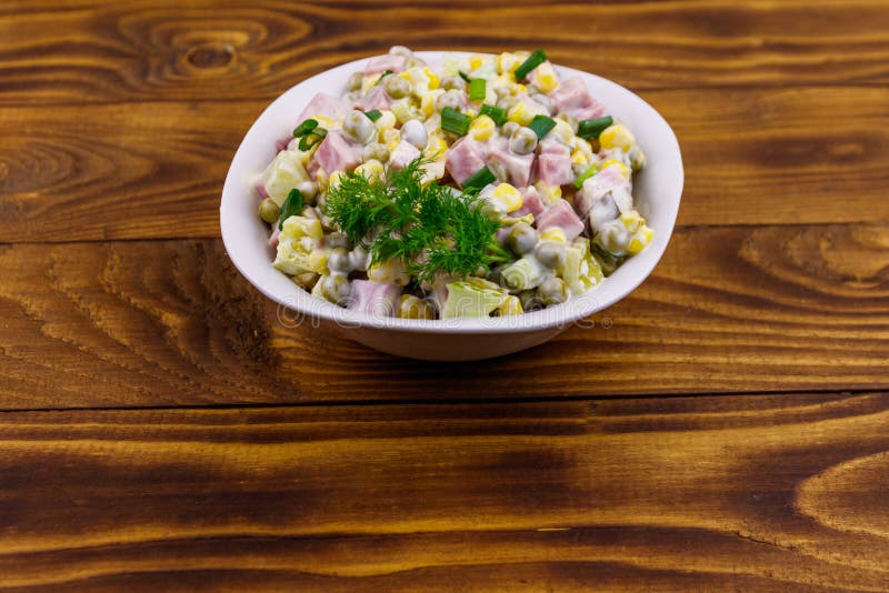 Salada saboroso com salsicha, a ervilha verde, milho enlatado, pimenta de sino, pepino e maionese na tabela de madeira fotos de stock royalty free Salada saboroso com salsicha, a ervilha verde, milho enlatado, pimenta de sino, pepino e maionese na tabela de madeira fotos de stock royalty free