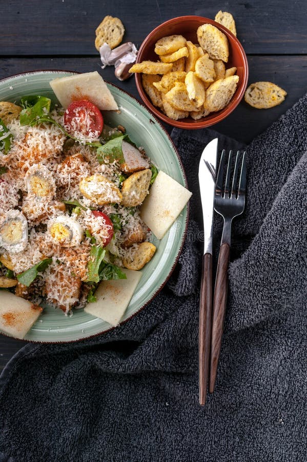 Salade de César en gros plan avec l'oeuf de caille, le poulet frit, le parmesan et les croûtons sur un fond rustique foncé Tir ve photos libres de droits