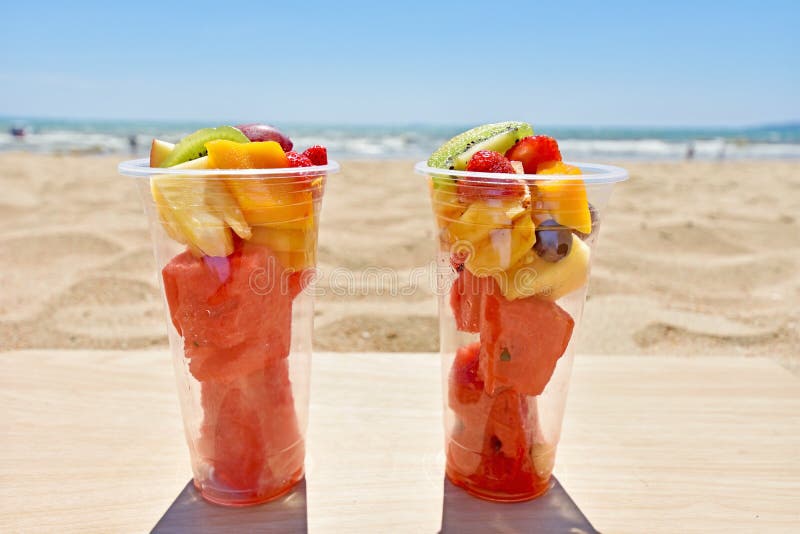 Salade de fruits dans des tasses en plastique à emporter sur la plage photographie stock Salade de fruits dans des tasses en plastique à emporter sur la plage photographie stock