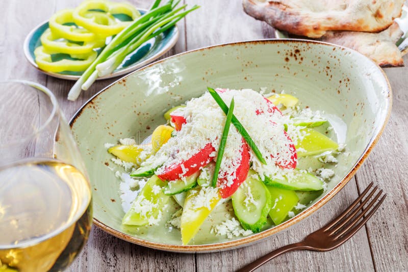 Salade fraîche avec les tomates-cerises, le concombre, le poivron doux et le parmesan et le verre de vin sur le fond en bois image libre de droits Salade fraîche avec les tomates-cerises, le concombre, le poivron doux et le parmesan et le verre de vin sur le fond en bois image libre de droits