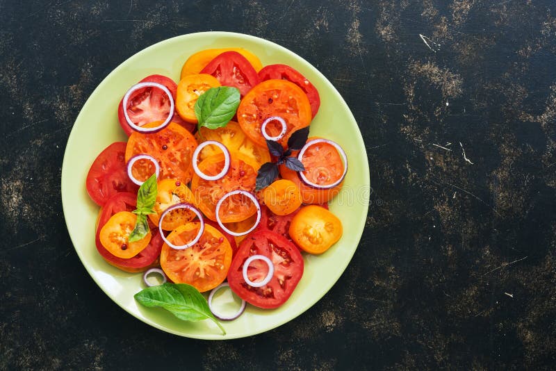 Salade fraîche rouge et jaune de tomate à l'oignon, basilic d'un plat vert, fond rustique foncé Vue supérieure, l'espace de copie images stock Salade fraîche rouge et jaune de tomate à l'oignon, basilic d'un plat vert, fond rustique foncé Vue supérieure, l'espace de copie images stock