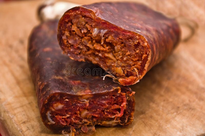 Salami on a wooden chopping board. Close-up of a home-made Romanian Babic Salami on a wooden chopping board (raw, dried salami containing a mix of pork and beef stock photo Salami on a wooden chopping board. Close-up of a home-made Romanian Babic Salami on a wooden chopping board (raw, dried salami containing a mix of pork and beef stock photo
