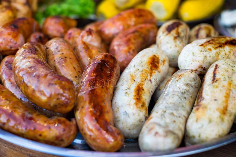 Salchicha fresca y perritos calientes que asan a la parrilla al aire libre en una parrilla de la barbacoa del gas fotos de archivo Salchicha fresca y perritos calientes que asan a la parrilla al aire libre en una parrilla de la barbacoa del gas fotos de archivo