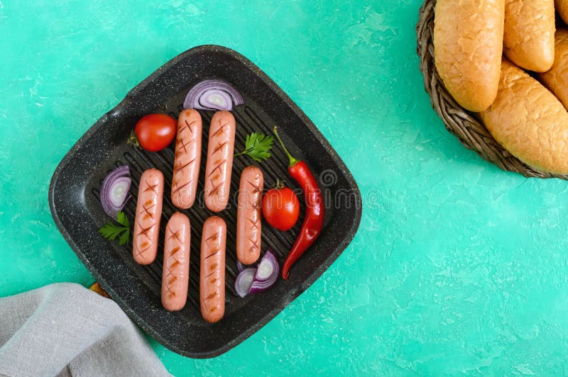 Salchichas asadas a la parrilla jugosas en la cacerola de la parrilla con las verduras y el bollo curruscante Visión superior imagen de archivo libre de regalías Salchichas asadas a la parrilla jugosas en la cacerola de la parrilla con las verduras y el bollo curruscante Visión superior imagen de archivo libre de regalías