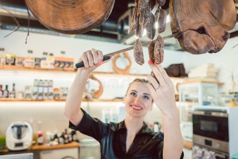 Sales clerk in deli cutting sausages to sell them stock photo Sales clerk in deli cutting sausages to sell them stock photo