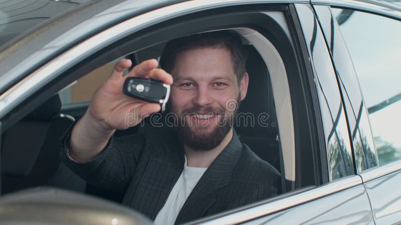 Sales manager handing over the keys to man that sitting in the car.