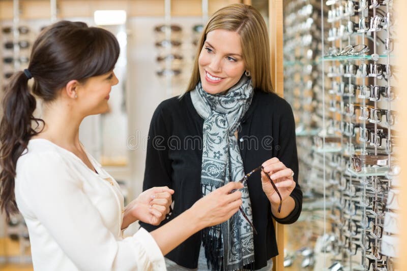 Salesgirl I klient Trzyma szkła W sklepie obraz royalty free Salesgirl I klient Trzyma szkła W sklepie obraz royalty free