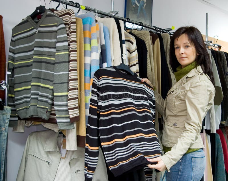 Na saleslady ukazuje jednu z mnoha svetry.