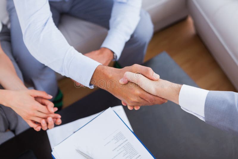 Salesman shaking hands with client with contract on the coffee table. Negotiating table stock images, royalty-free photos and pictures