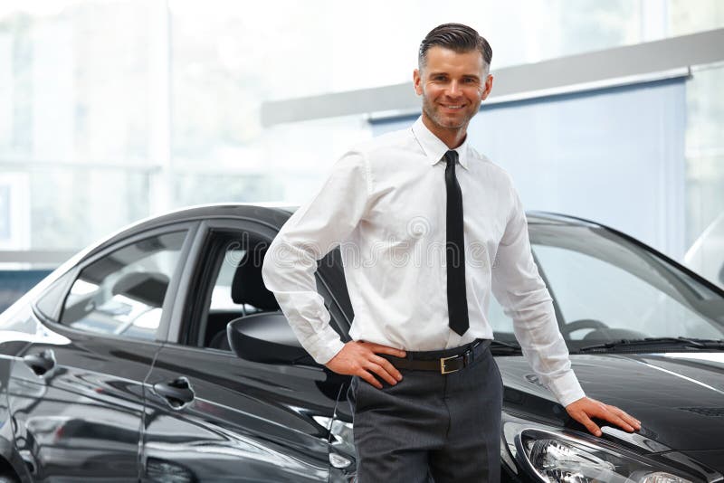 Salesman Stands Near Brand New Car. Car Showroom stock photos Salesman Stands Near Brand New Car. Car Showroom stock photos
