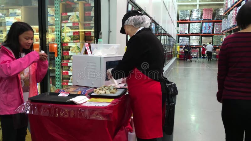 Saleswoman offering spring roll food samples to customers inside Costco store