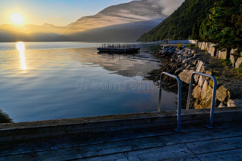 Salida del sol de la madrugada en un pequeño puerto en un fiordo foto de archivo Salida del sol de la madrugada en un pequeño puerto en un fiordo foto de archivo