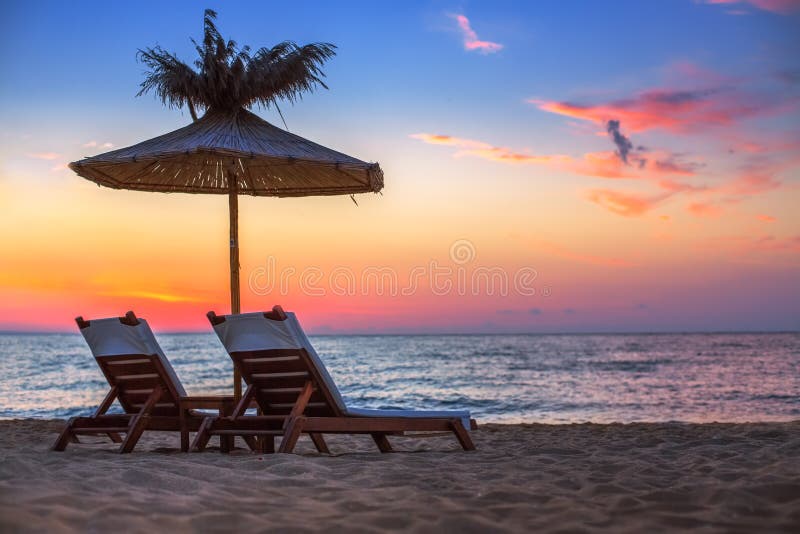 Vivid sunrise on a beautiful sandy beach with sunshade and chaise-longue. Vivid sunrise on a beautiful sandy beach with sunshade and chaise-longue