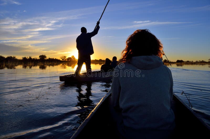 Saling dans le delta d'Okavango au coucher du soleil, Botswana