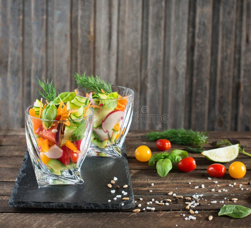 Fresh vegetarian salad in glasses served on slate board with ingredients around, selective focus. Fresh vegetarian salad in glasses served on slate board with ingredients around, selective focus.