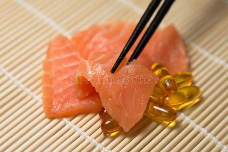Salmon Sashimi misto con le capsule dell'olio di pesce con la gru a benna del bastoncino fotografie stock libere da diritti Salmon Sashimi misto con le capsule dell'olio di pesce con la gru a benna del bastoncino fotografie stock libere da diritti