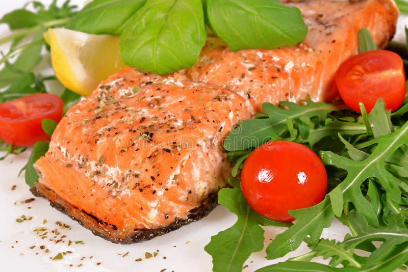 Salmones asados a la parrilla con arugula y tomates fotografía de archivo Salmones asados a la parrilla con arugula y tomates fotografía de archivo
