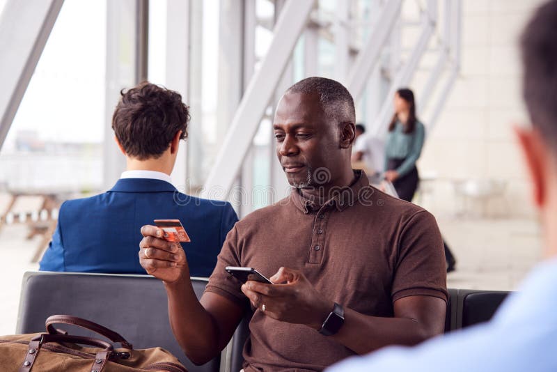 Salon de départ de Sitting In Airport d'homme d'affaires qui font des achats en ligne en utilisant le téléphone portable