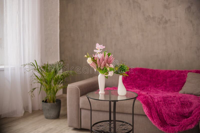 Salone interno domestico accogliente con un sofà marrone e un vaso con i fiori ed elementi della decorazione su una piccola tavol immagini stock libere da diritti Salone interno domestico accogliente con un sofà marrone e un vaso con i fiori ed elementi della decorazione su una piccola tavol immagini stock libere da diritti