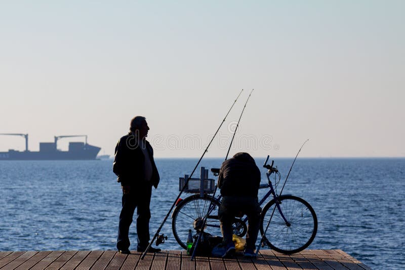 SALONIKI, GRIECHENLAND - 25. DEZEMBER 2015: Schattenbild von alten Fischern auf Saloniki-Seeseite, Ägäisches Meer stockbild SALONIKI, GRIECHENLAND - 25. DEZEMBER 2015: Schattenbild von alten Fischern auf Saloniki-Seeseite, Ägäisches Meer stockbild