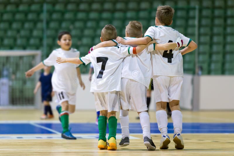 Indoor football soccer match for children. Happy kids together after winning futsal game. Chldren celebrate sport victory. Youth sport triumph. Indoor football soccer match for children. Happy kids together after winning futsal game. Chldren celebrate sport victory. Youth sport triumph