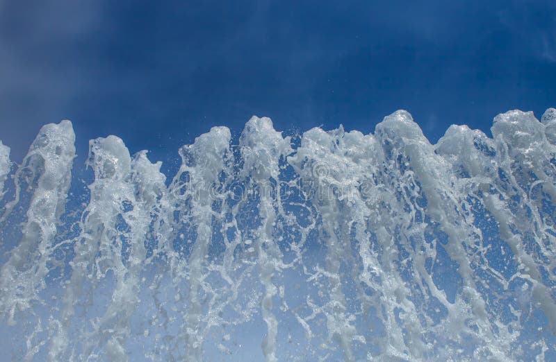 Salpicar el agua de una fuente en fondo del cielo azul fotos de archivo Salpicar el agua de una fuente en fondo del cielo azul fotos de archivo