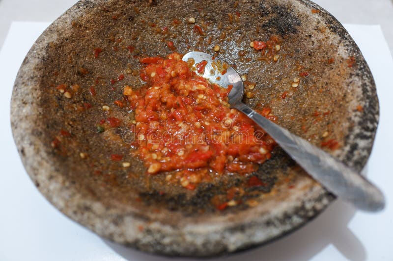 Sambal or traditional chili sauce from Indonesia, freshly made using stone mortar and spoon, Isolated in white background, food, stock photo. Sambal or traditional chili sauce from Indonesia, freshly made using stone mortar and spoon, Isolated in white background, food, stock photo.