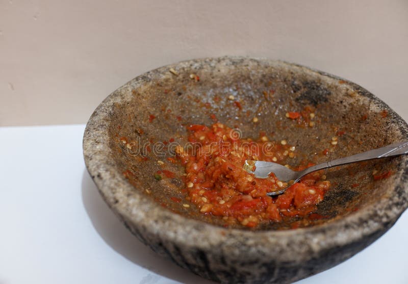Sambal or traditional chili sauce from Indonesia, freshly made using stone mortar and spoon, Isolated in white background, food, stock photo. Sambal or traditional chili sauce from Indonesia, freshly made using stone mortar and spoon, Isolated in white background, food, stock photo.