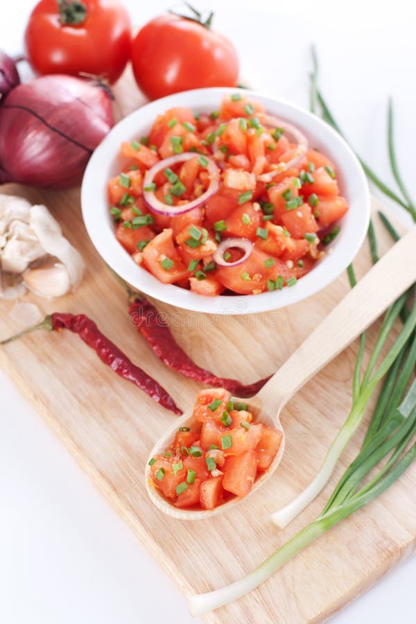 Salsa in a bowl on a wooden board and ingredients