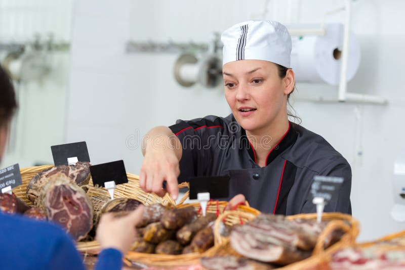 Salsiccia secca del servizio femminile del macellaio immagine stock libera da diritti Salsiccia secca del servizio femminile del macellaio immagine stock libera da diritti