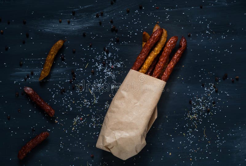 Salsiccie affumicate su una struttura di carta su un fondo scuro con vigore fotografie stock libere da diritti Salsiccie affumicate su una struttura di carta su un fondo scuro con vigore fotografie stock libere da diritti