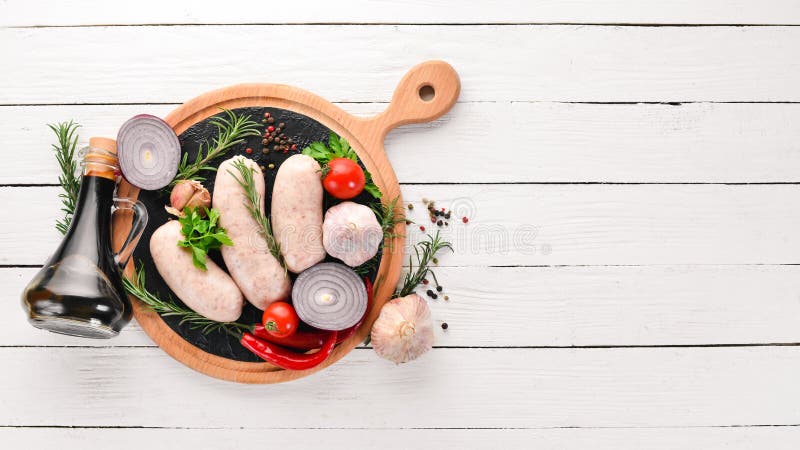 Salsiccie crude con le spezie e le erbe barbecue Su un fondo di legno bianco fotografia stock Salsiccie crude con le spezie e le erbe barbecue Su un fondo di legno bianco fotografia stock