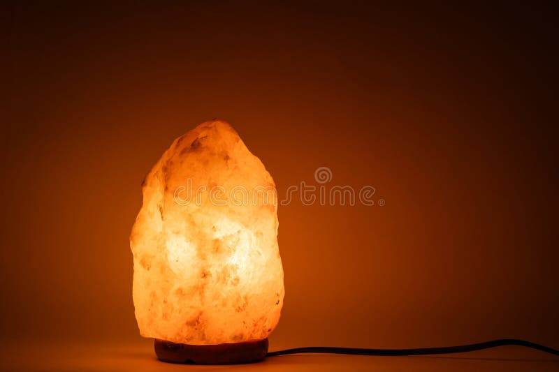 Salt lamp glows with warm bright orange light. stock photography