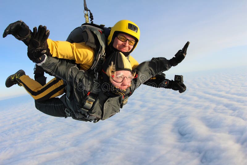 Saltar em queda livre em tandem Os Skydivers estão voando acima das nuvens brancas foto de stock Saltar em queda livre em tandem Os Skydivers estão voando acima das nuvens brancas foto de stock