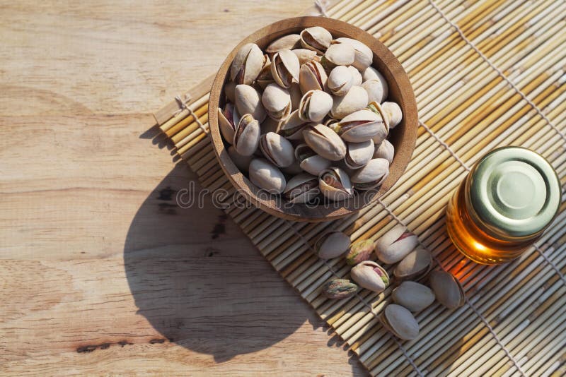 Salted pistachio in wooden bowl on wood table with green banana leaf background, copy space royalty free stock photos Salted pistachio in wooden bowl on wood table with green banana leaf background, copy space royalty free stock photos